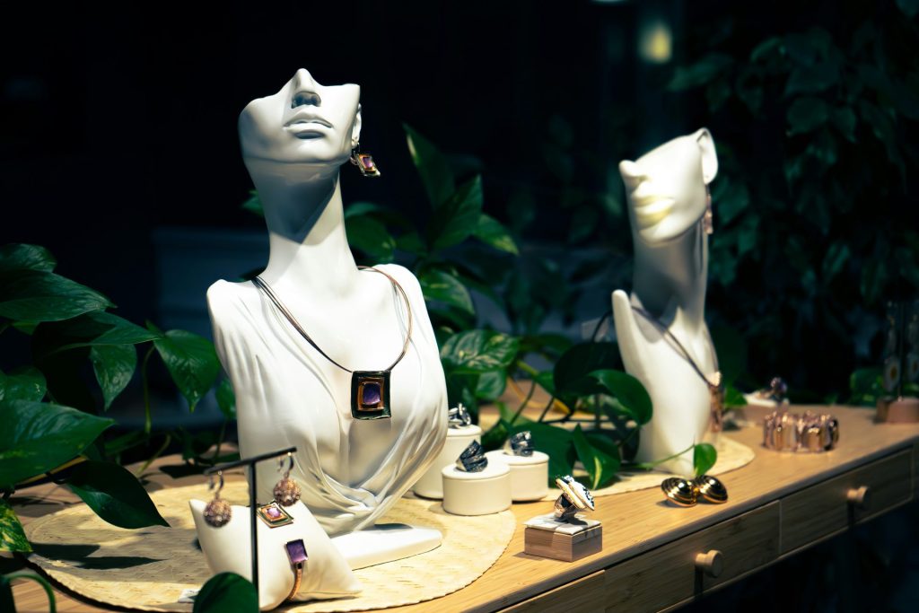 Joyas expuestas en maniquíes y soportes con plantas.